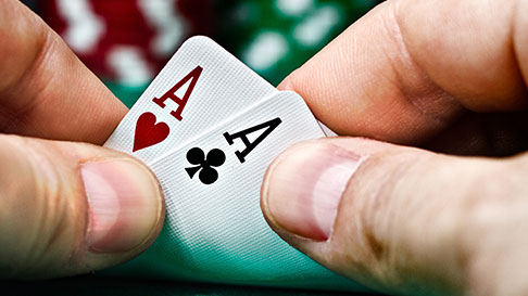 finger holding cards with faded chips in background